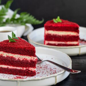 Cake Red velvet on two white plates, two servings. On a black background. Birthday, holidays, sweets.